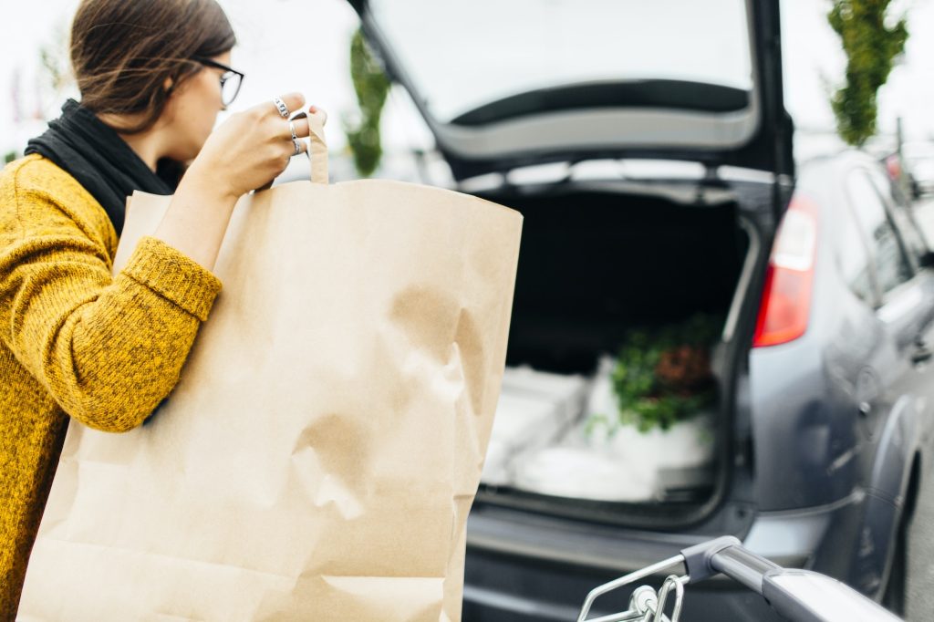 Young woman loading shopping bag into trunk of car